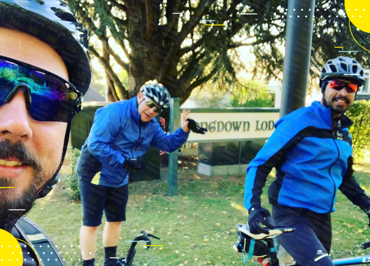 A group of cyclists posing for a photo in front of a sign.