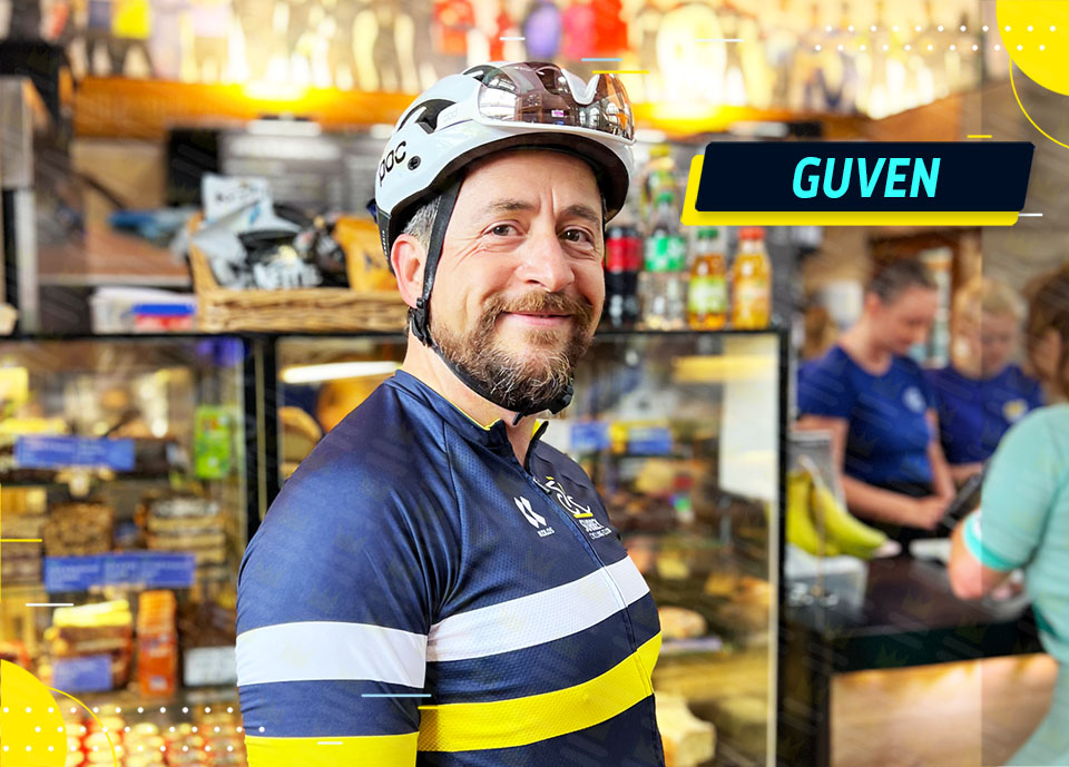 A man in a blue shirt is standing in front of a bakery.